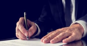 Businessman signing document at desk with pen