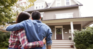 Couple embracing in front of suburban home