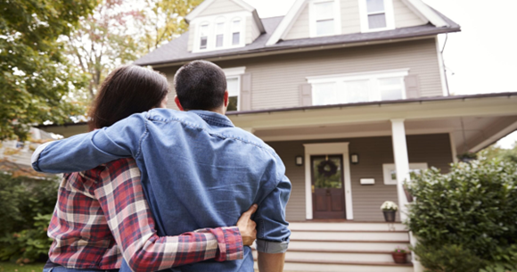 Couple embracing in front of suburban home